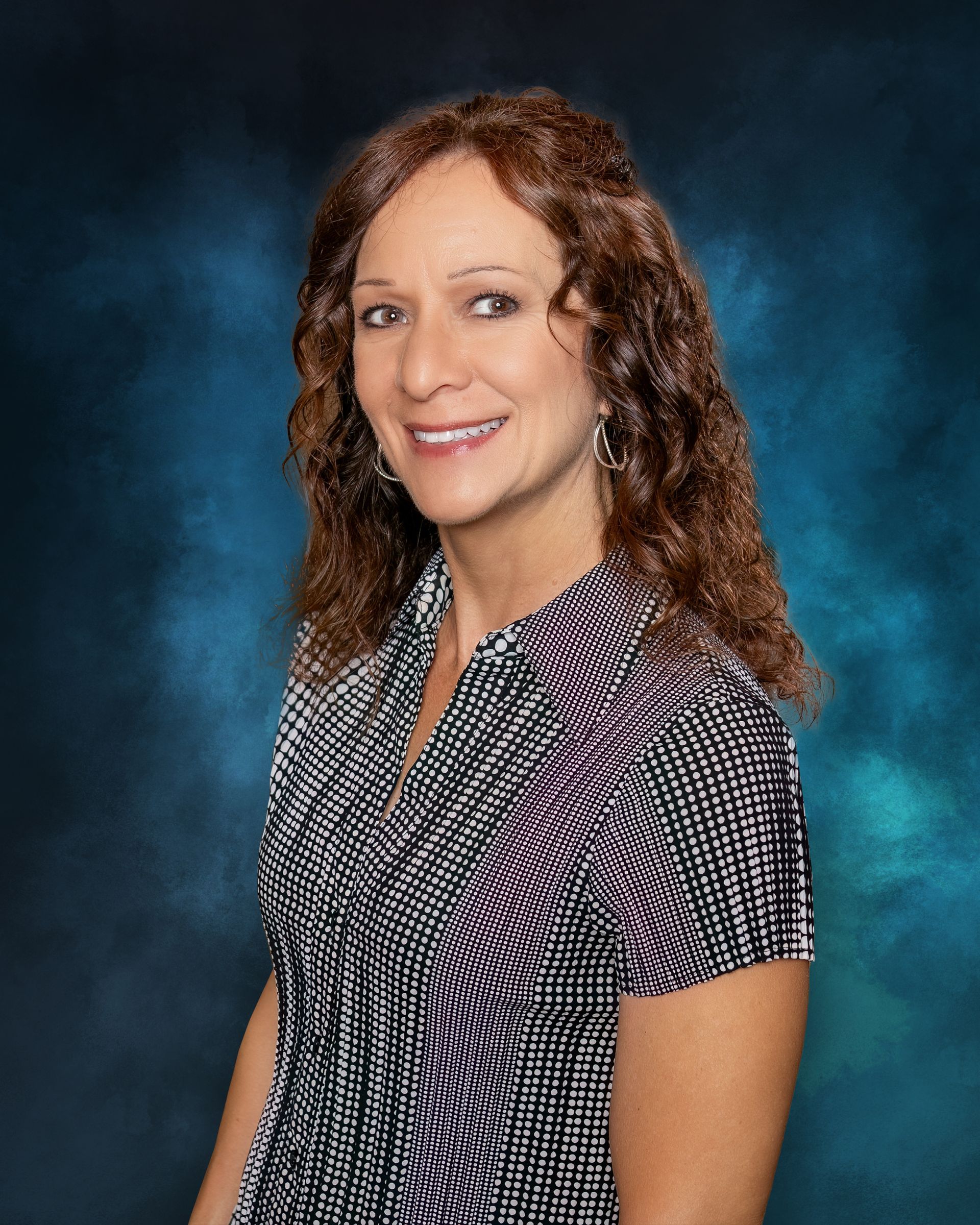A woman with long brown hair is smiling for the camera.