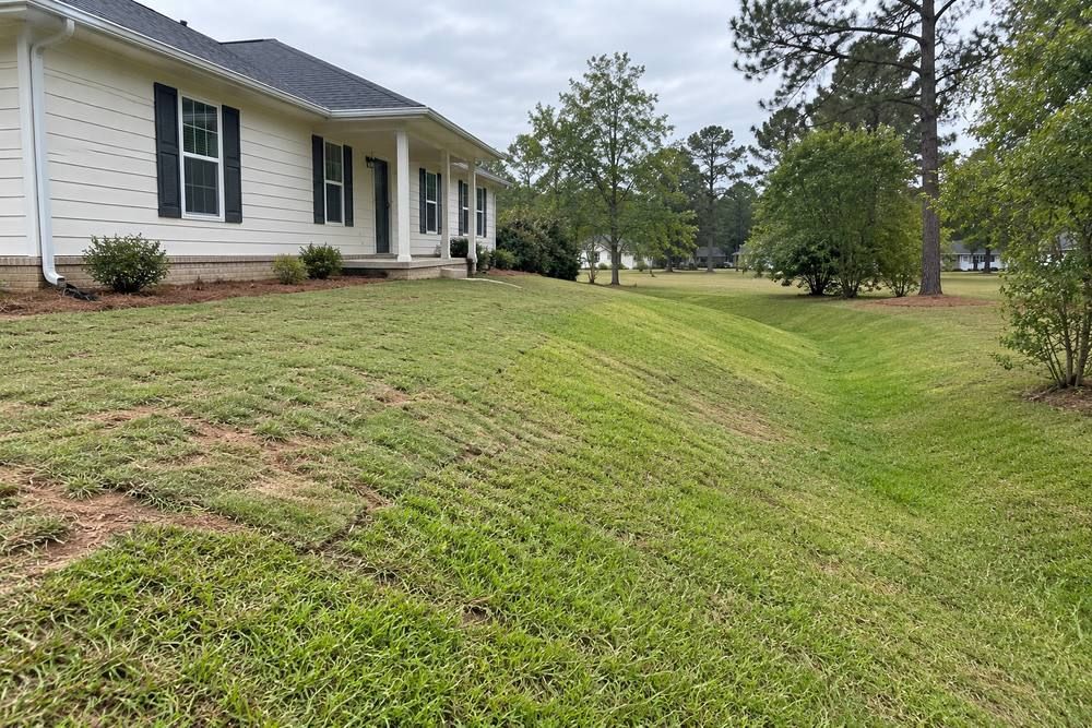 Graded lawn sloping away from a home into a grass swale.