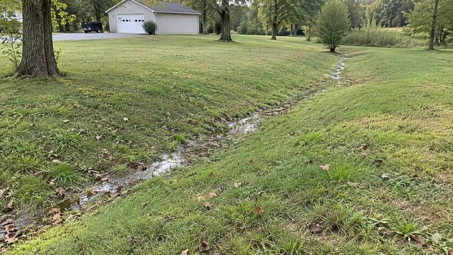 Shallow grass swale across a residential yard.