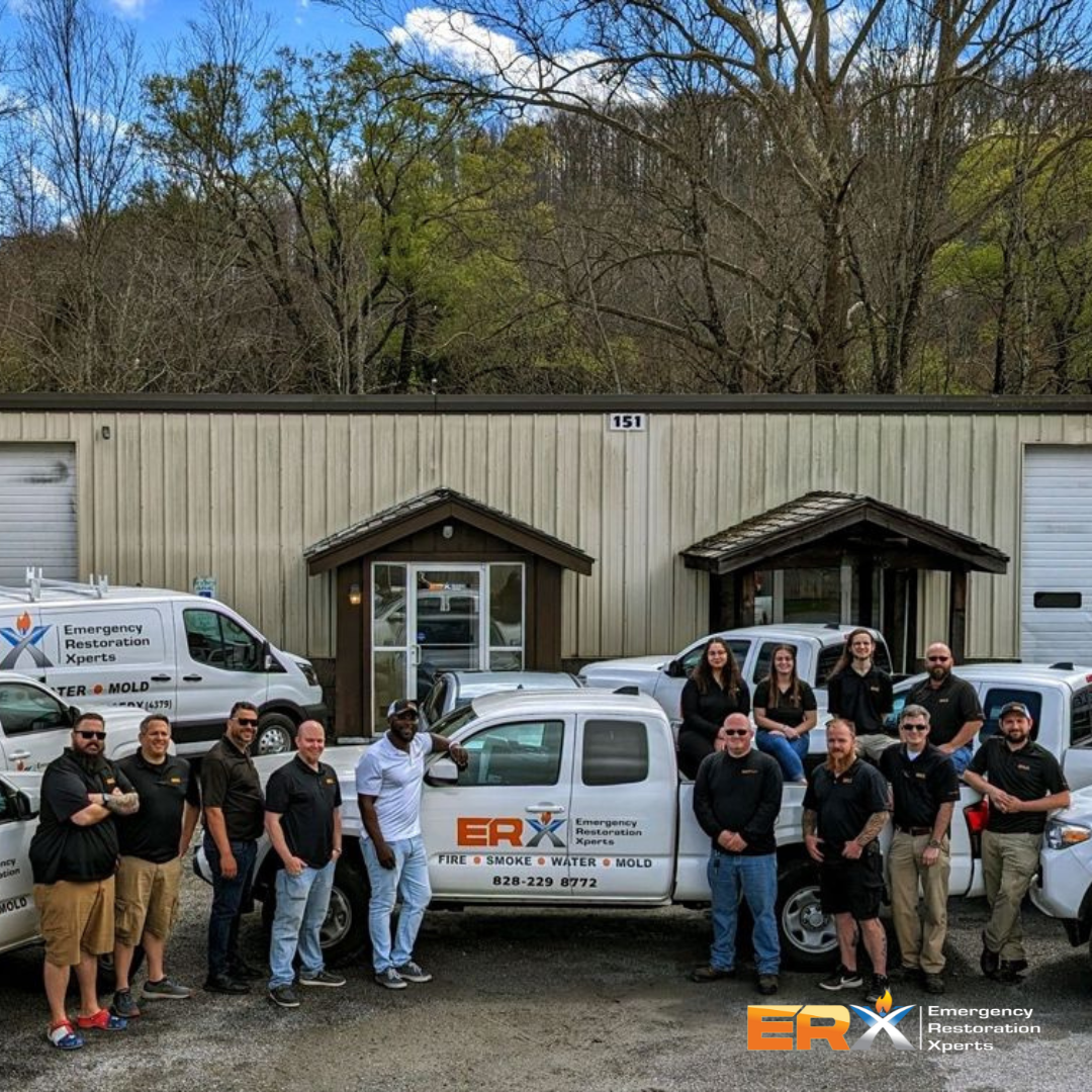 Crew posing with white service vans outside a beige garage building on a cloudy day.