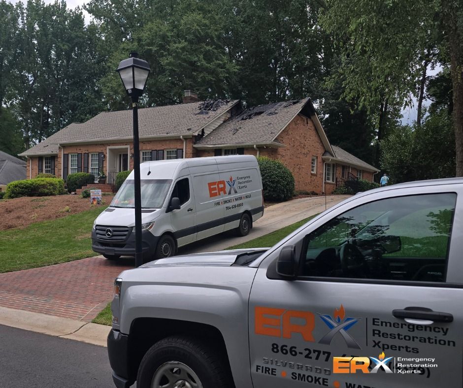 Two ERX Emergency Restoration Services vans parked outside a brick house on a tree-lined street.