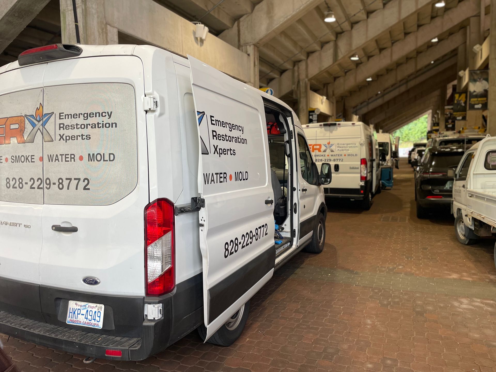 White utility vans parked inside a warehouse, one with company branding visible.