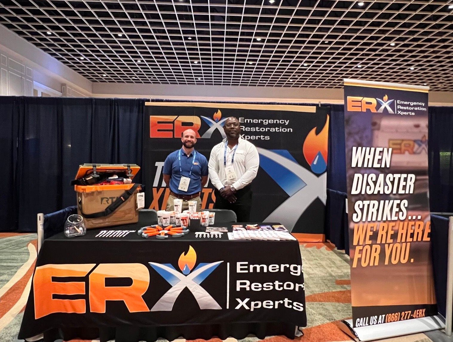 ERX disaster response booth with two people, tools, and banner reading “When disaster strikes, we’re here for you.”