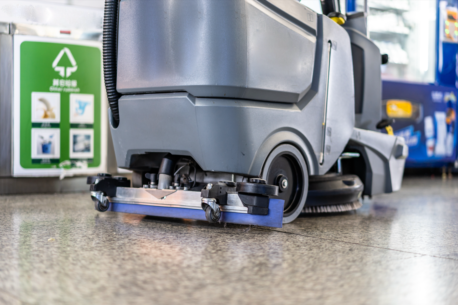 Floor scrubber cleaning a wet concrete floor in a warehouse aisle