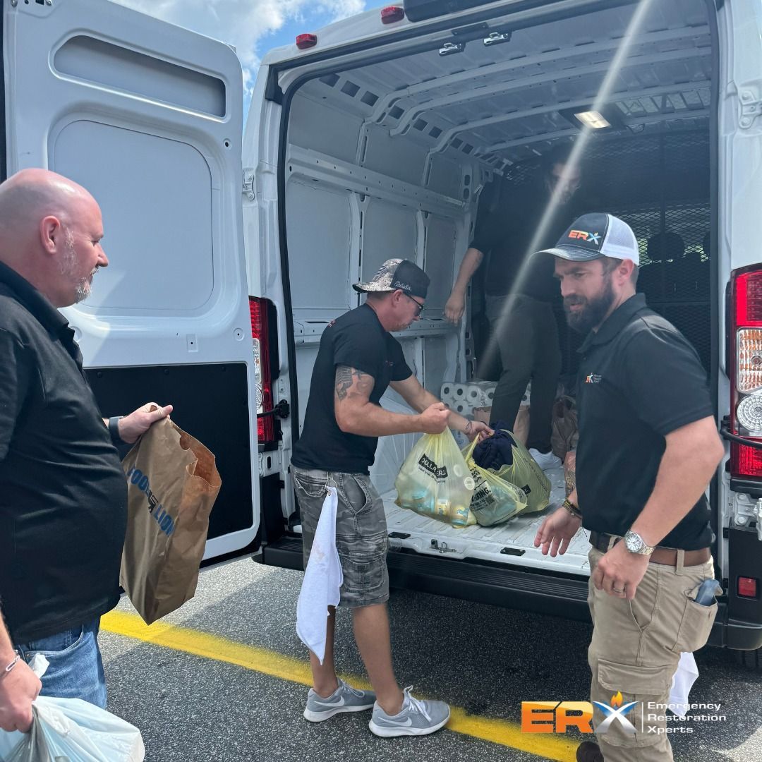 Three men loading bags into the back of a white cargo van at a curbside.