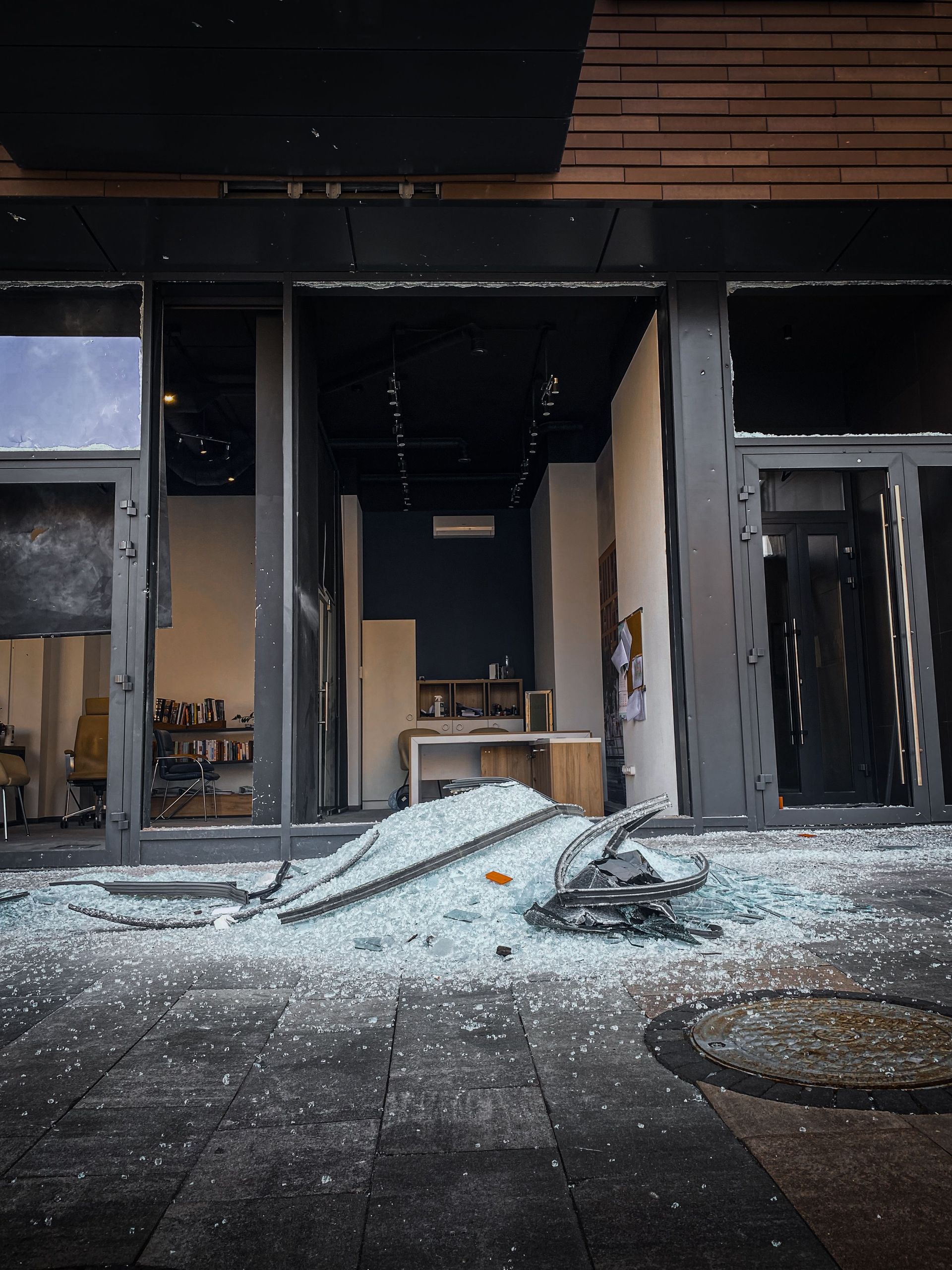 Abandoned storefront interior with shattered glass and debris on the floor
