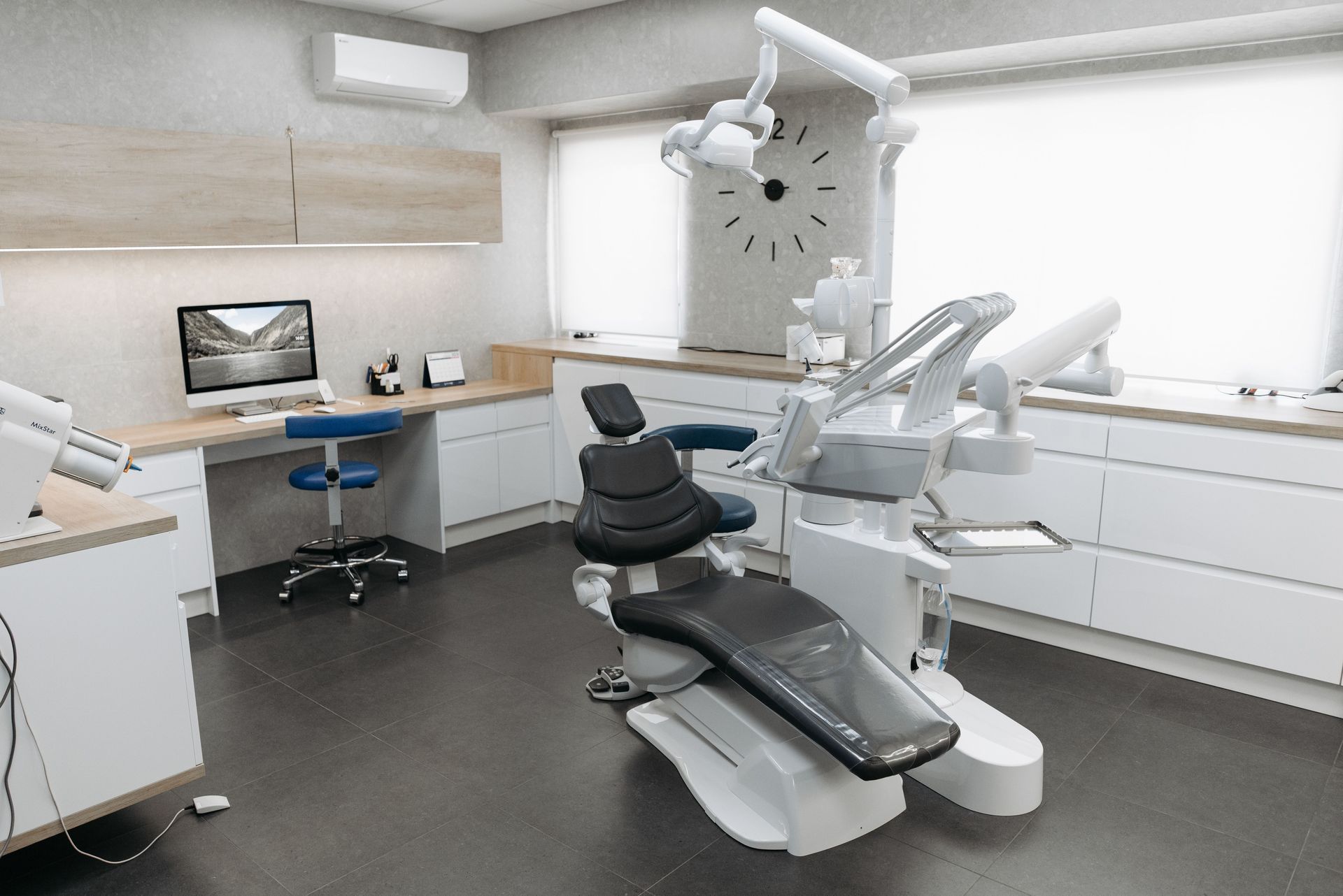 Modern dental exam room with chair, overhead light, and computer workstation
