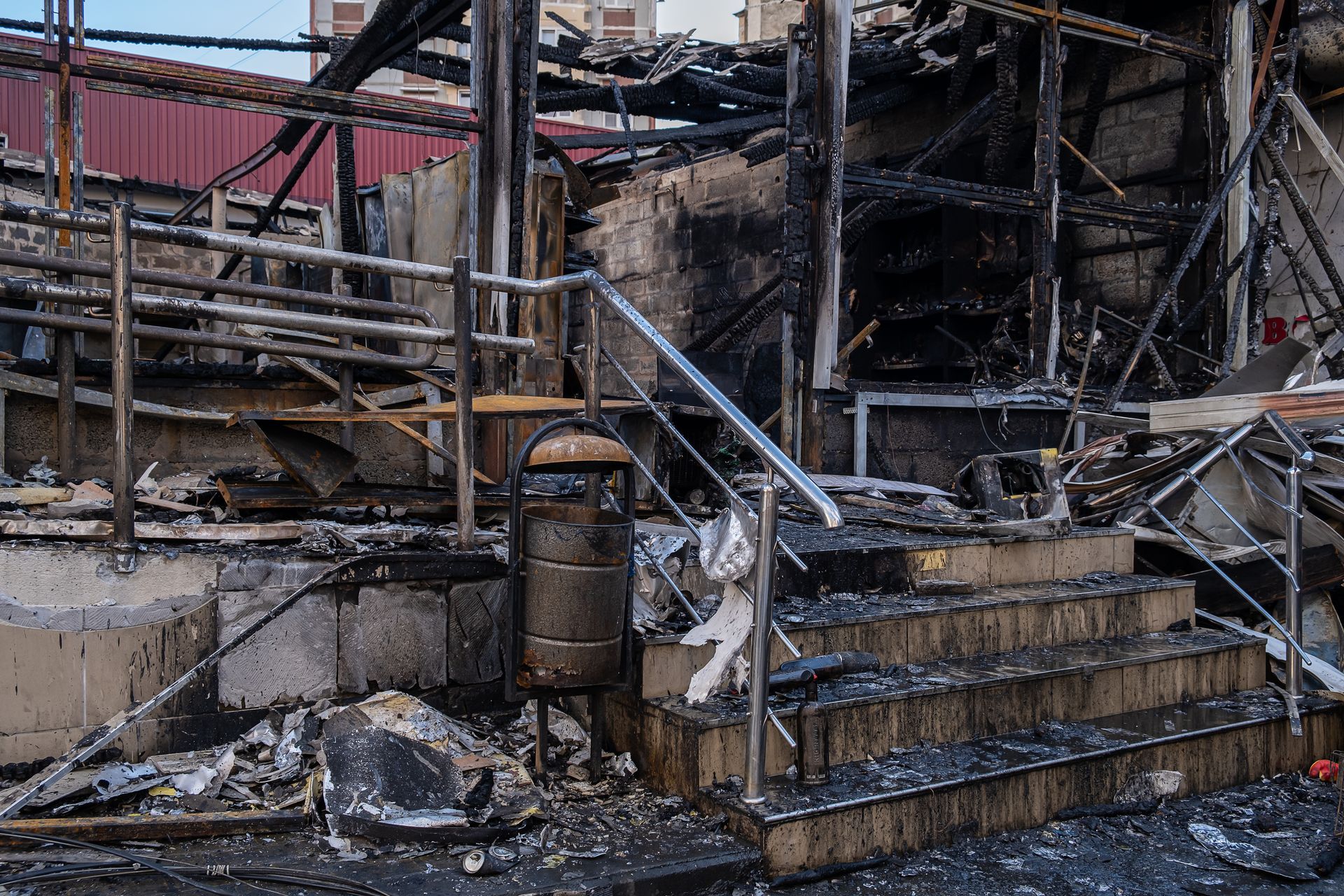 Charred building interior with collapsed stairs, burned debris, and smoke-damaged walls