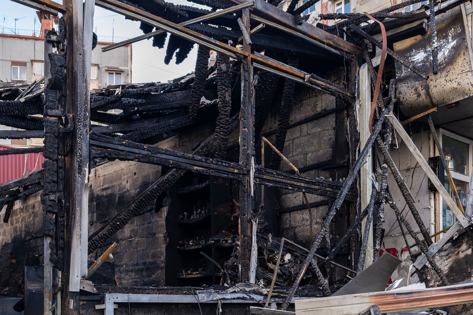 Charred remains of a burned building with collapsed metal framing and debris