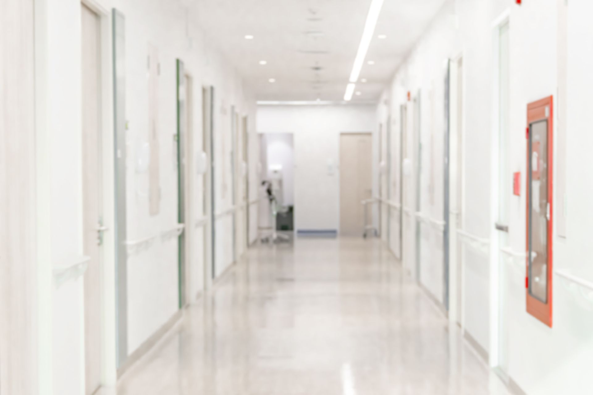 Bright, empty hospital hallway with white walls, polished floors, and doors on both sides