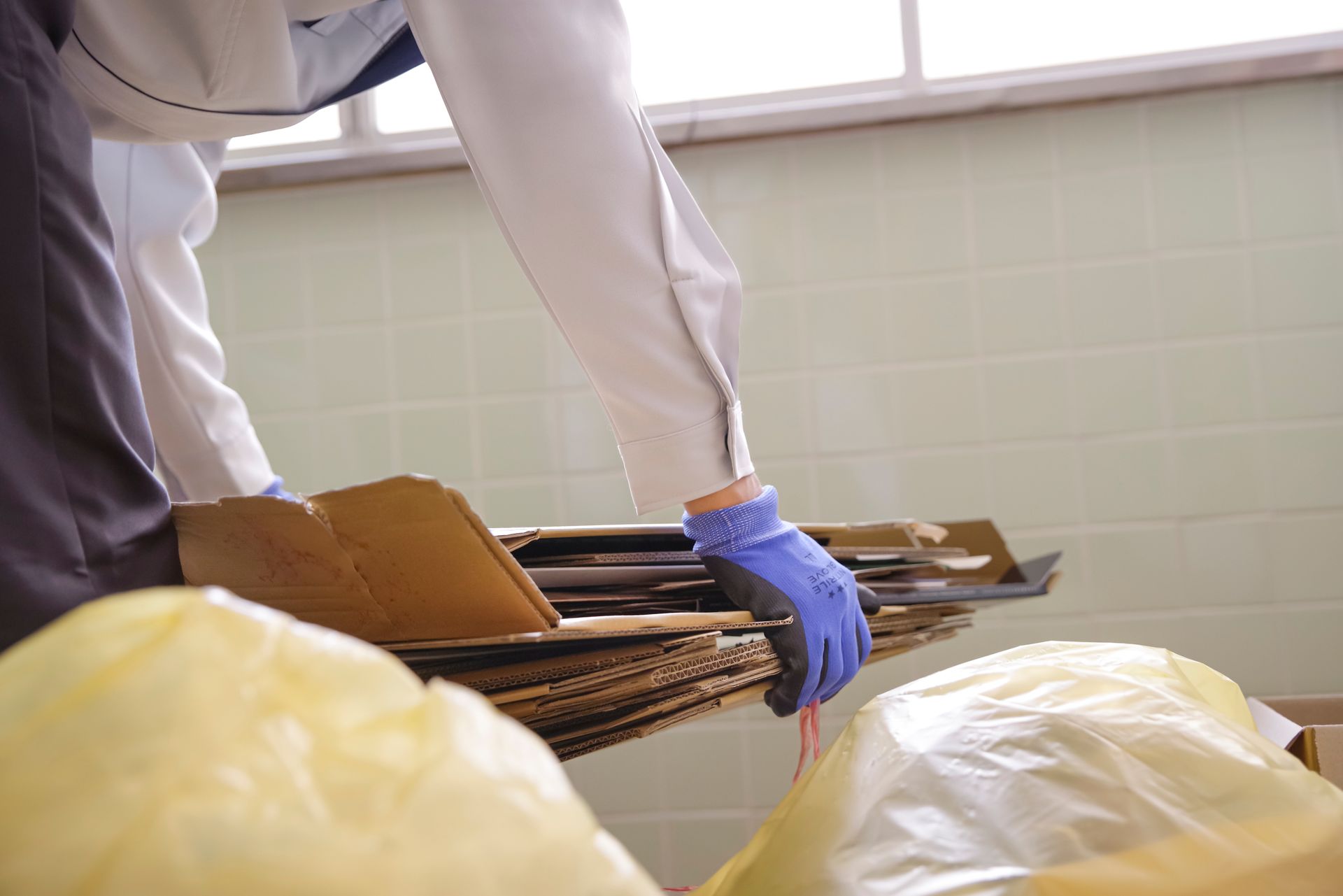 Gloved worker handling metal trays in a kitchen or food prep area