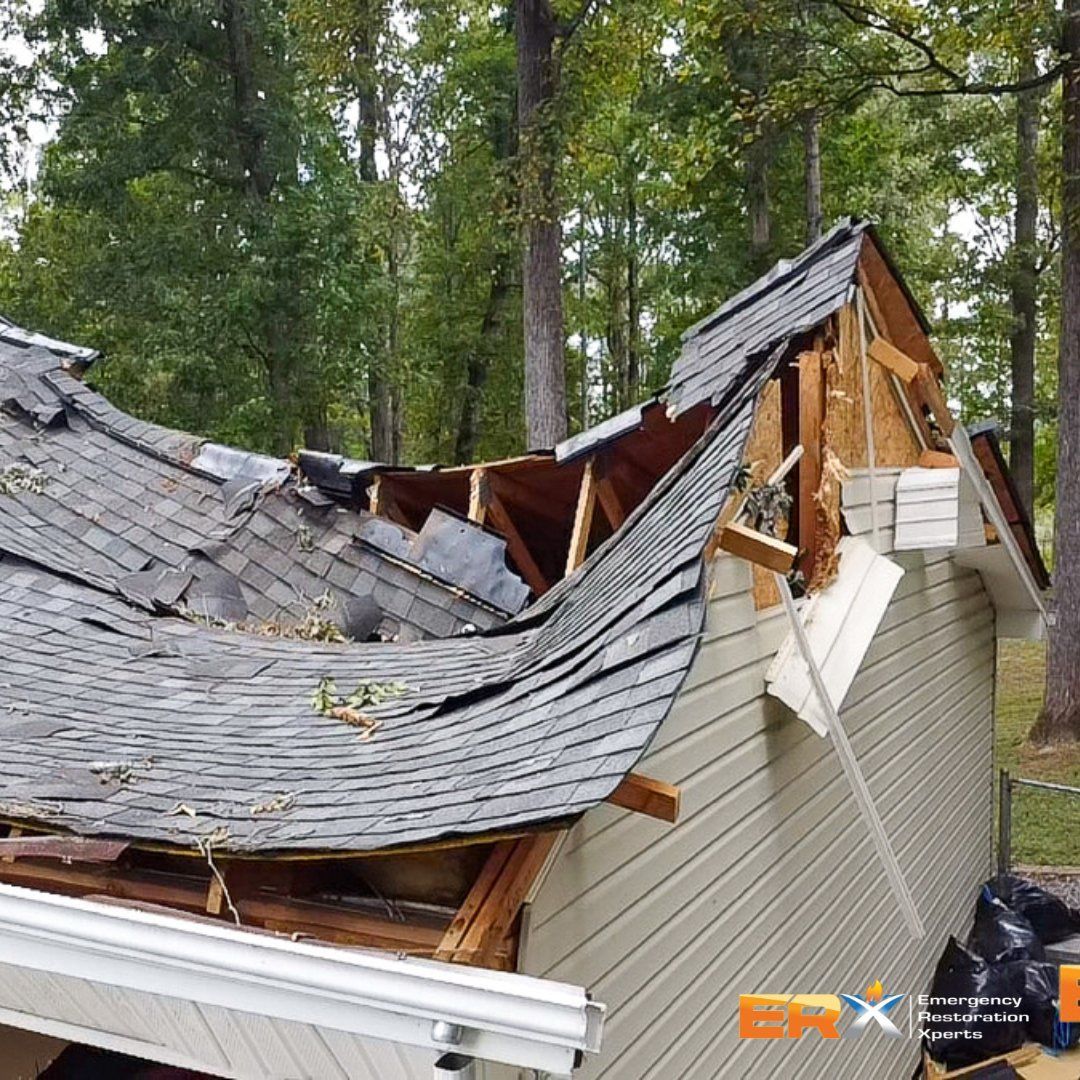 Collapsed house roof with severe storm damage and broken shingles in a wooded area