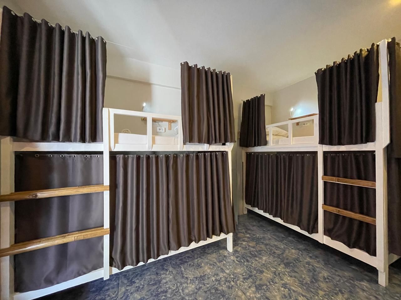 Bunk beds with brown curtains in a white-walled room.