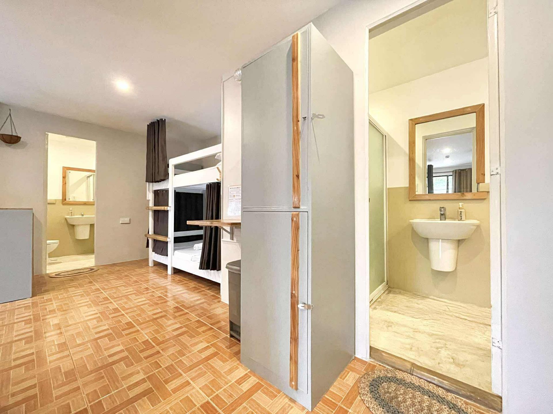 Hostel room with bunk beds, a tall cabinet, and a bathroom visible.
