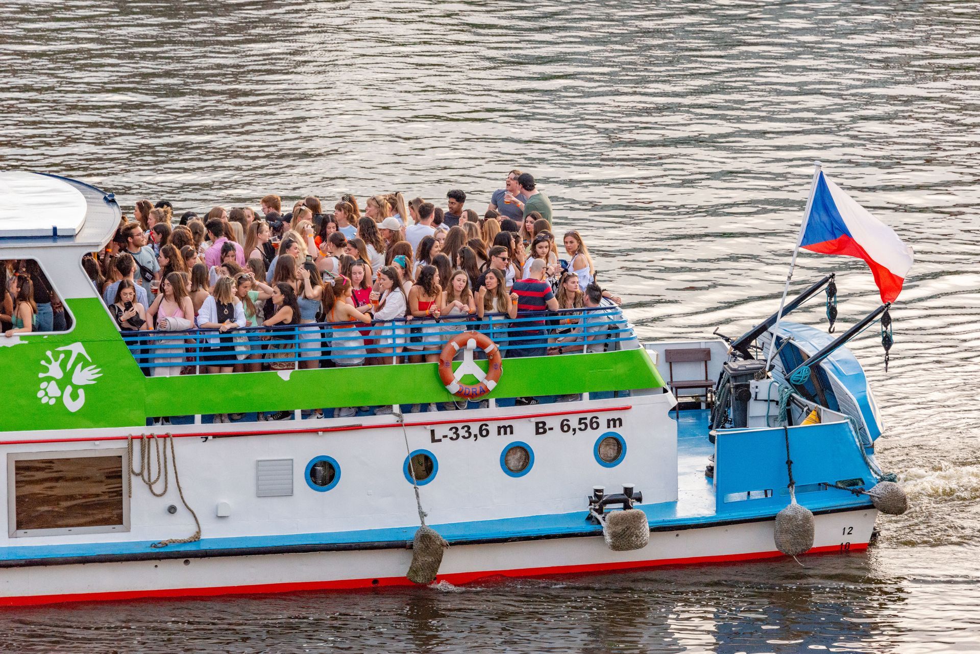 Blue boat with people on the water in a tropical cove, lush green hillside in the background.
