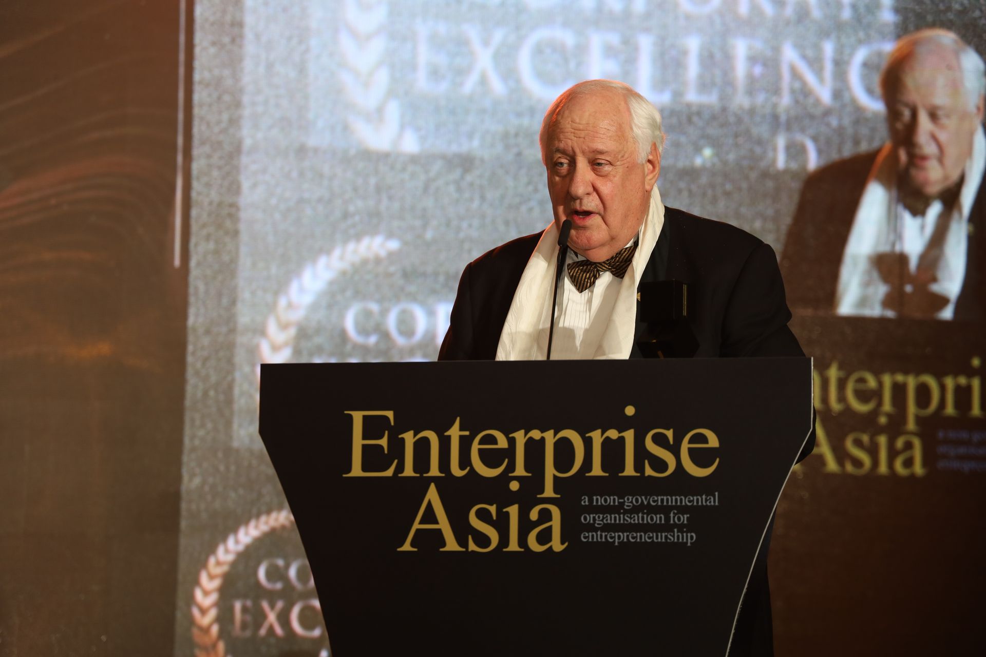 Man in suit speaking at Enterprise Asia awards, standing behind a podium.
