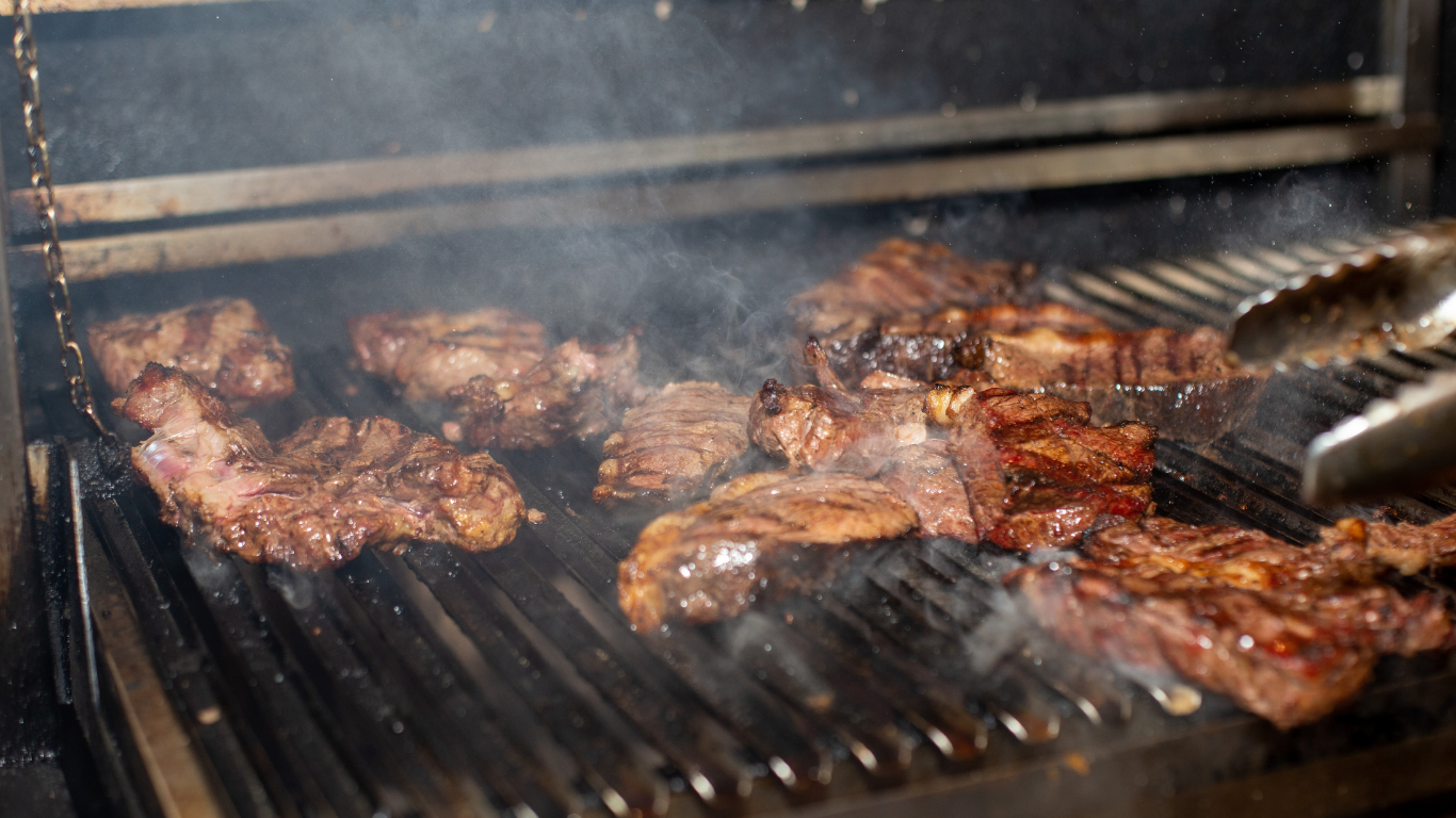Steaks grilling on a smoky grill, tongs ready to flip the meat.