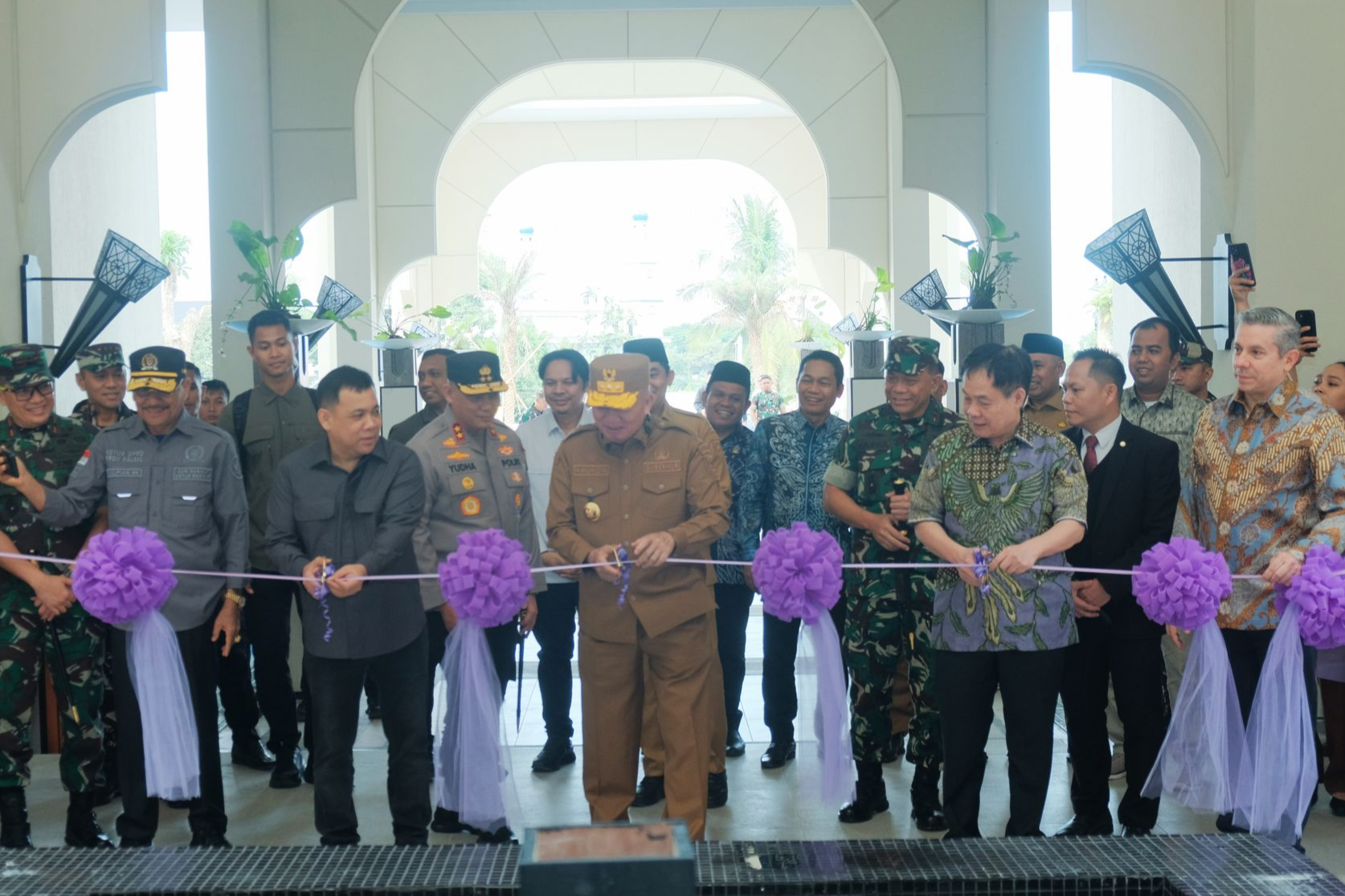 Officials cutting a ribbon at an opening ceremony, purple ribbons and decorations.
