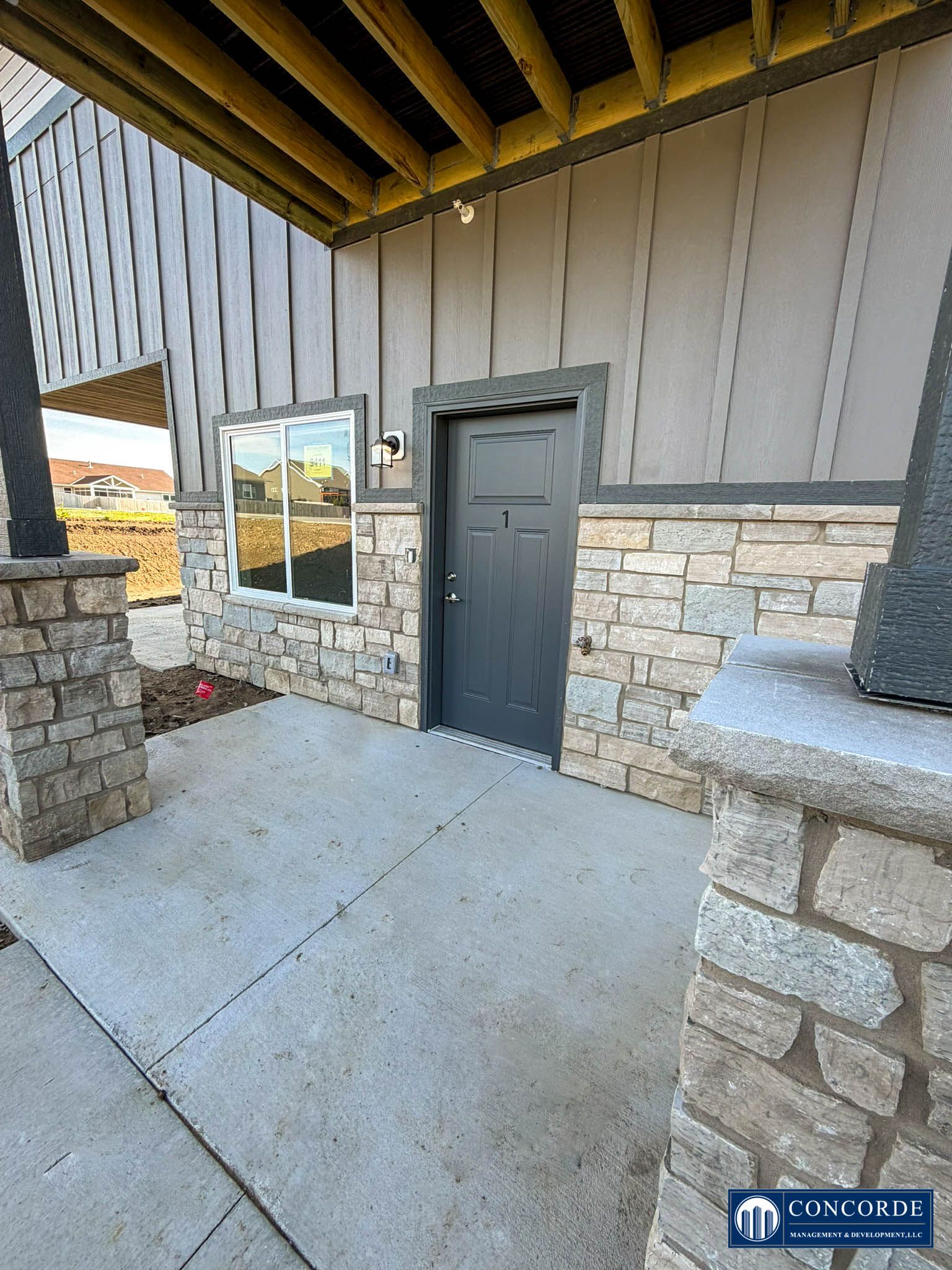 Stone exterior entry with black door, window, and covered concrete porch