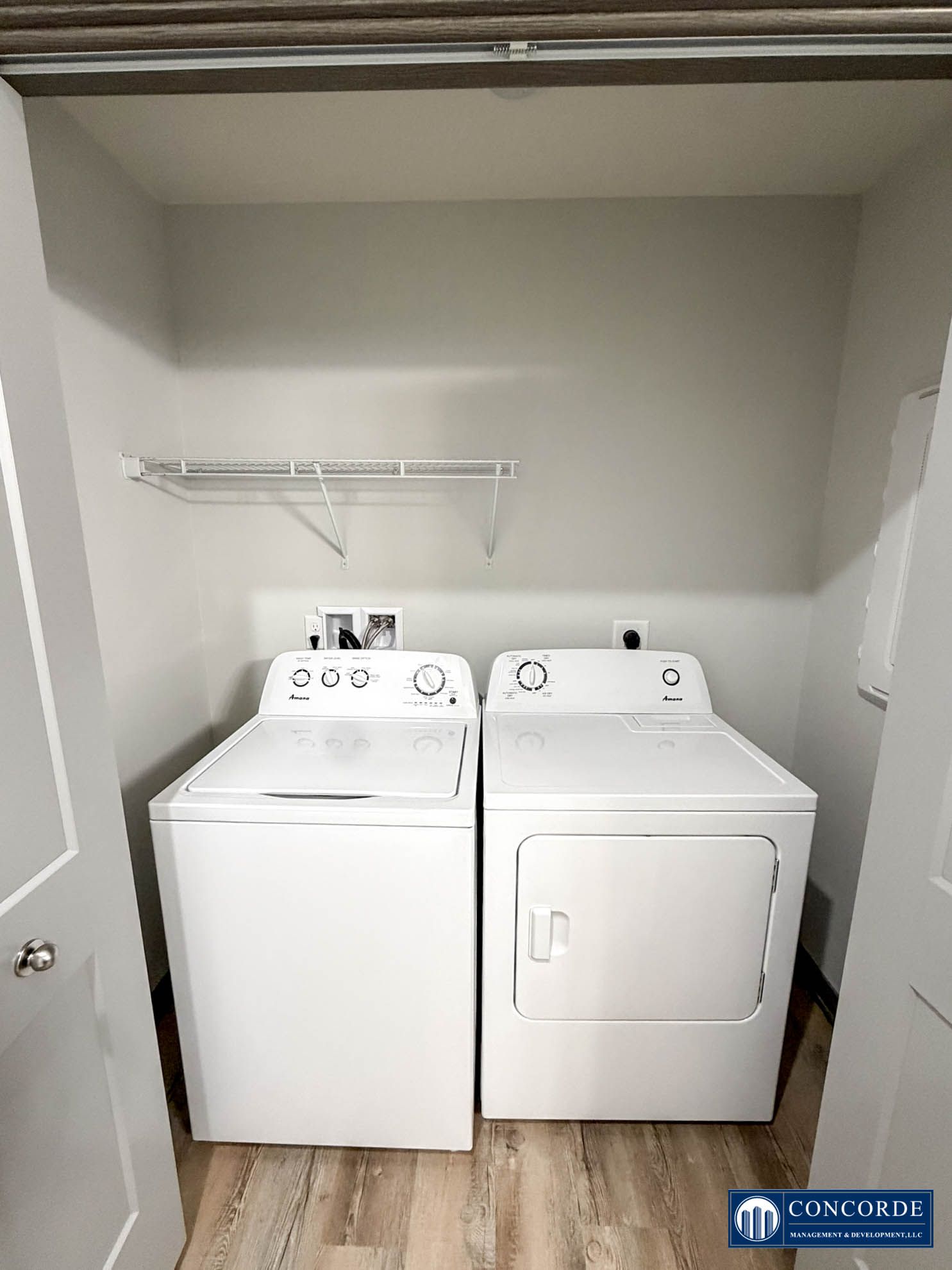 Laundry closet with white washer and dryer under a shelf and hanging rod