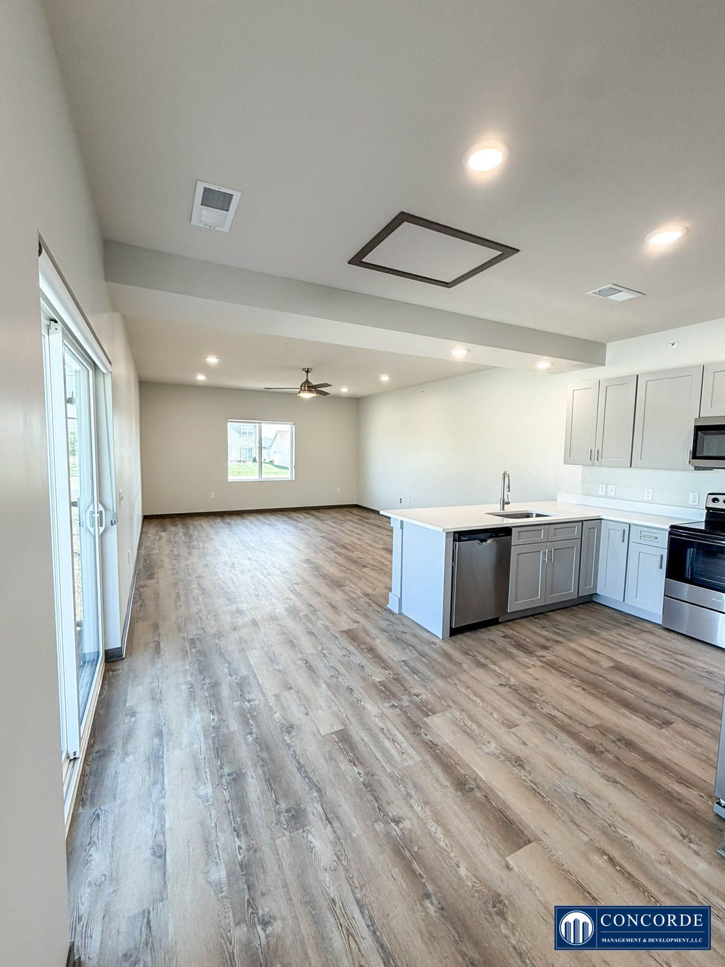 Bright open kitchen and living area with light wood floors, white cabinets, and island.