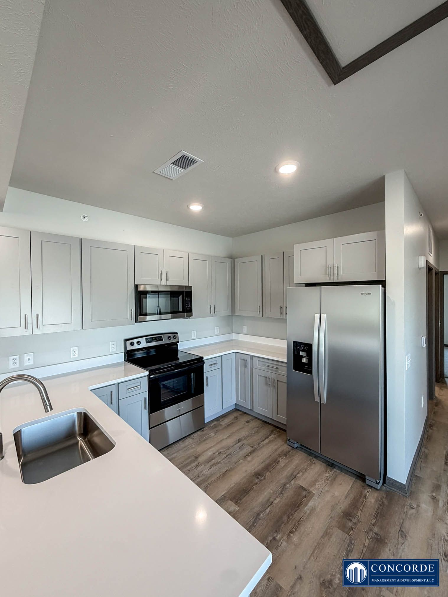 Bright modern kitchen with white cabinets, stainless steel appliances, and a wood floor