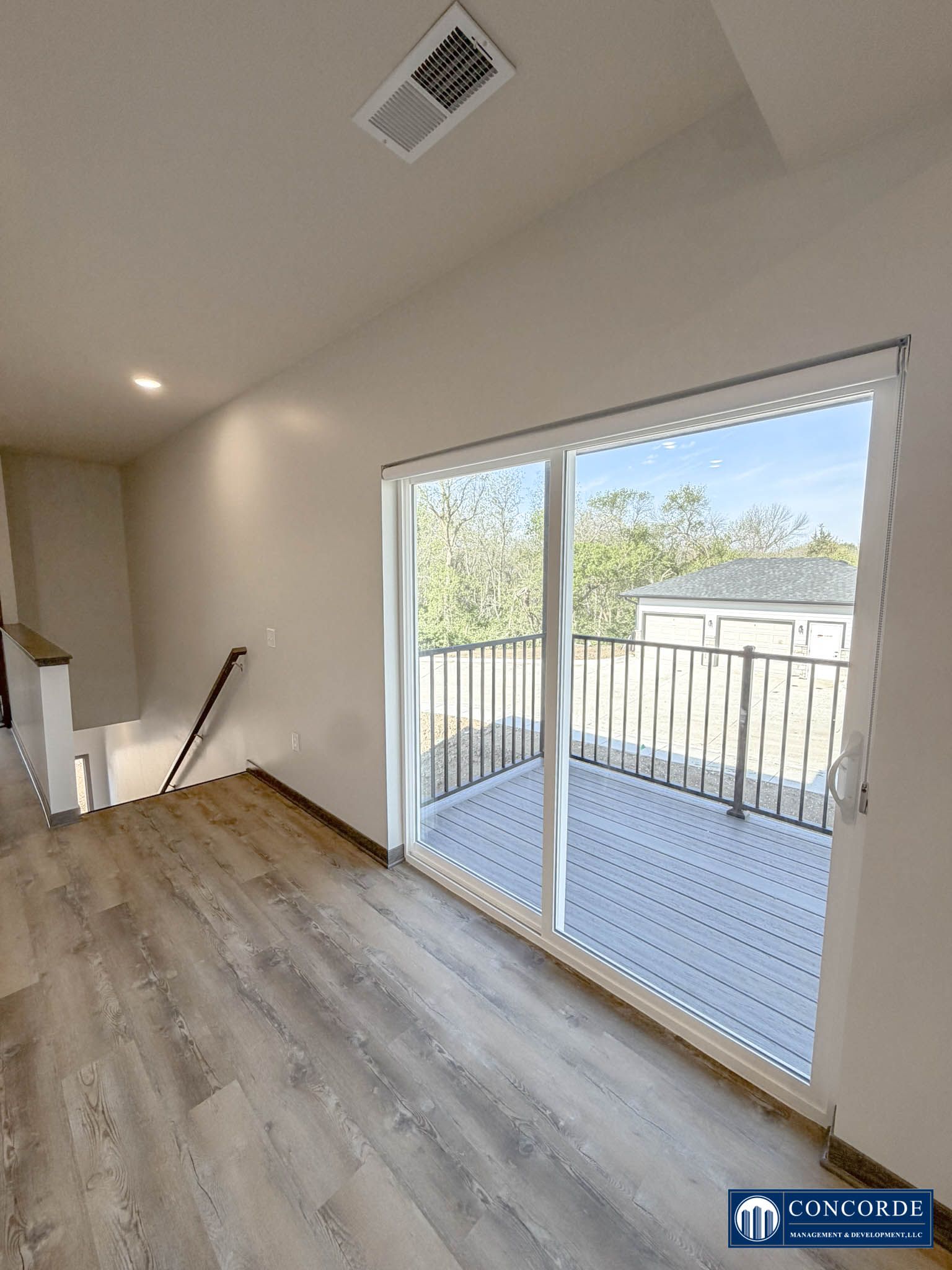 Empty room with wood floors and sliding glass doors opening to a small balcony.