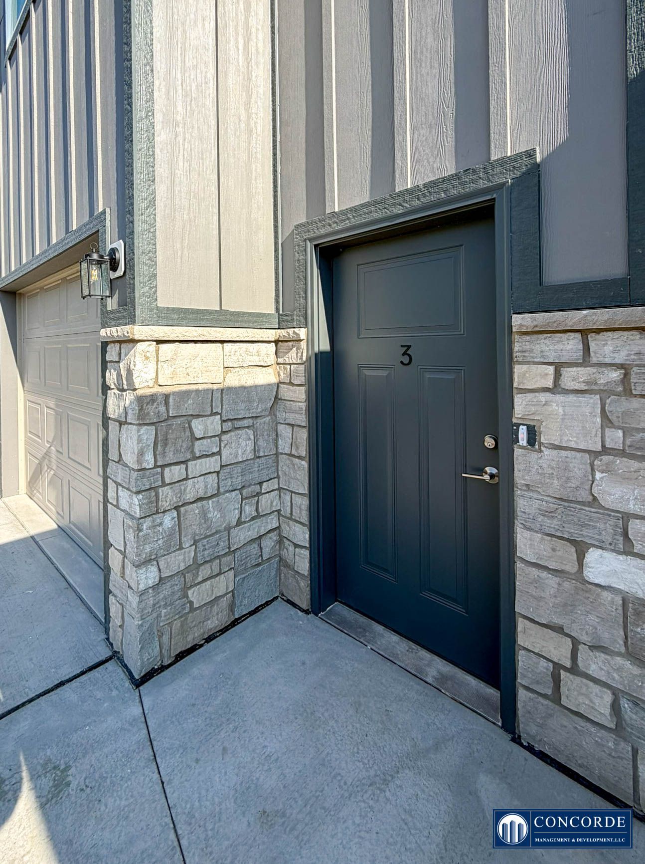Exterior entrance with dark blue door and stone trim on a gray building