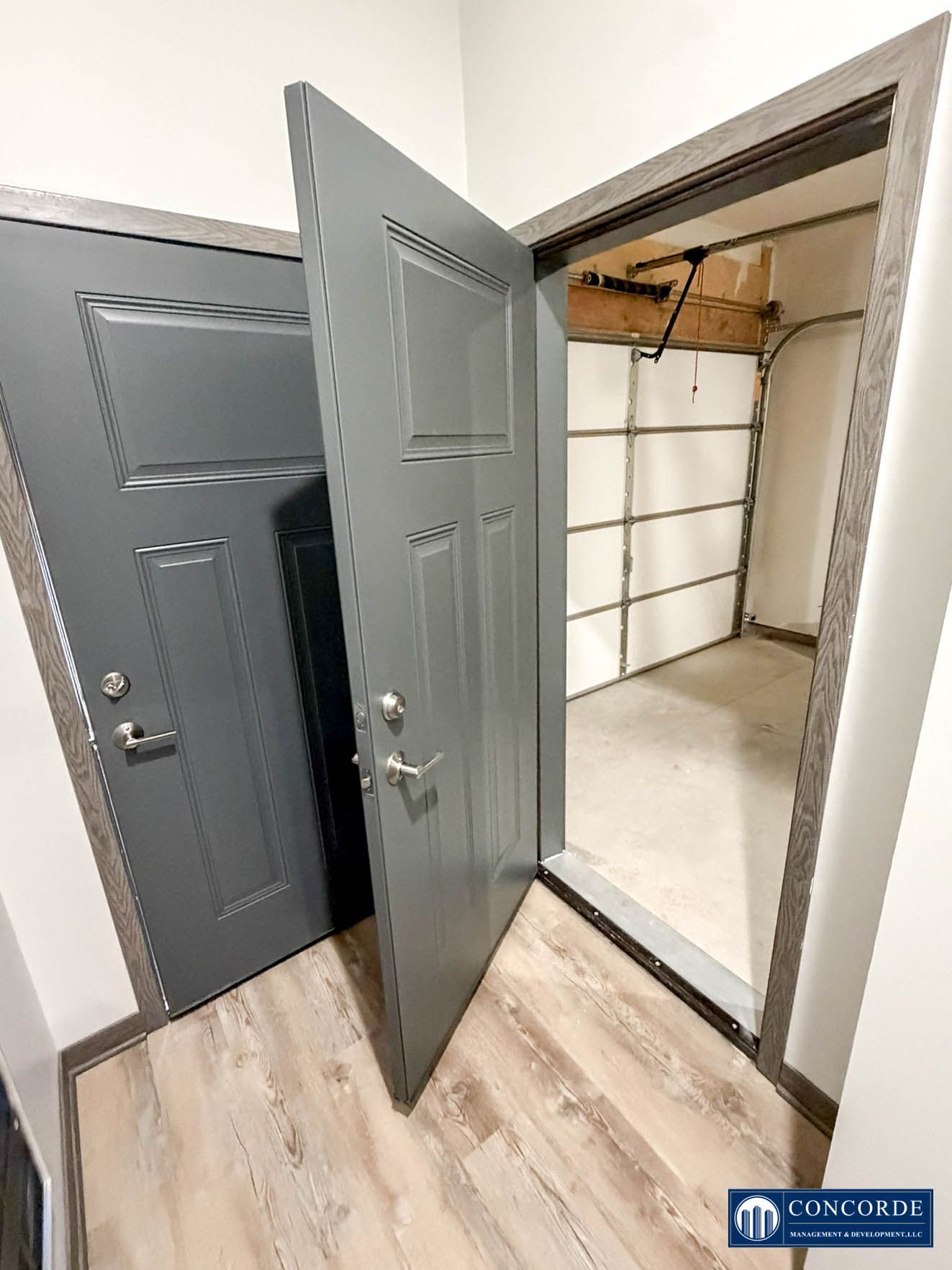 Gray front door and open closet doors in a hallway, showing a small storage space inside.