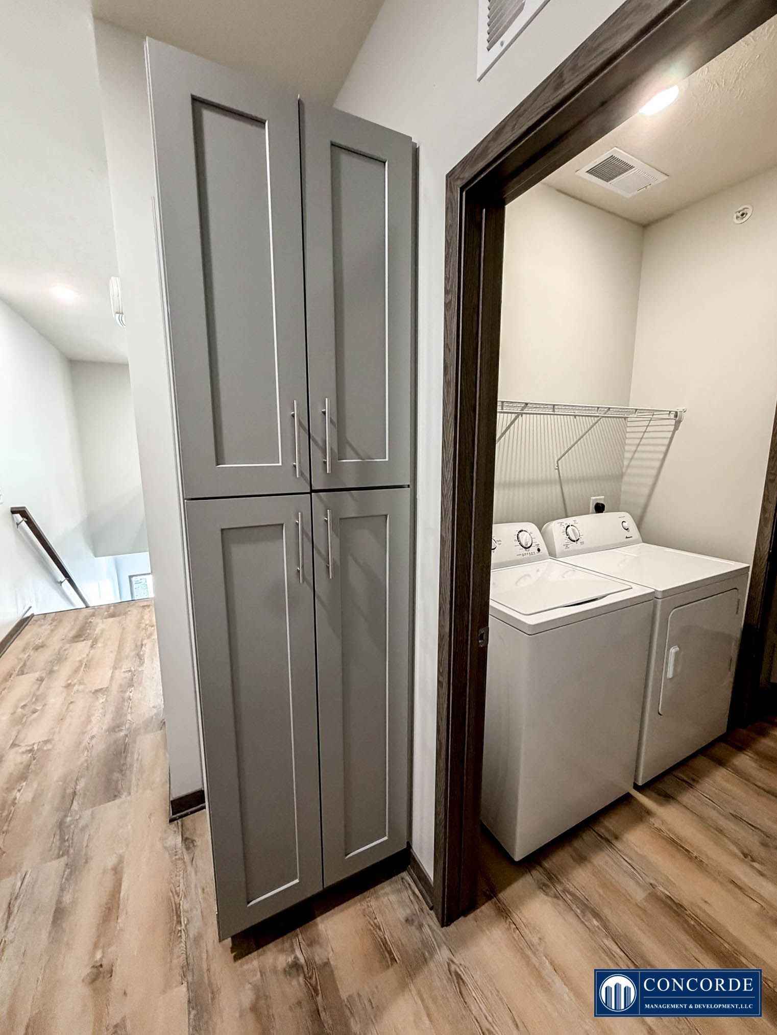 Hallway with tall gray cabinet beside a laundry nook with white washer and wire drying rack