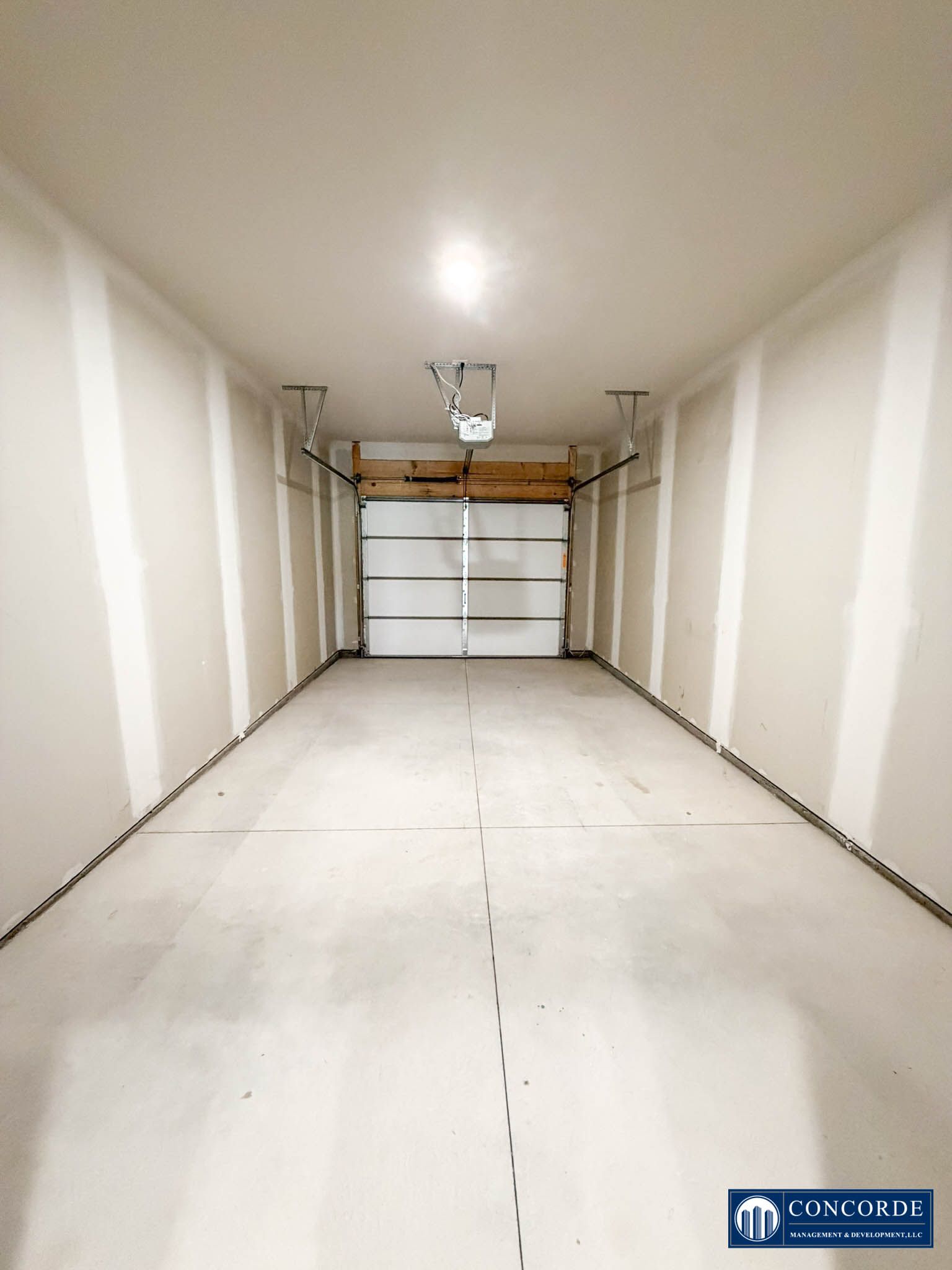 Empty white garage interior with closed overhead door and concrete floor