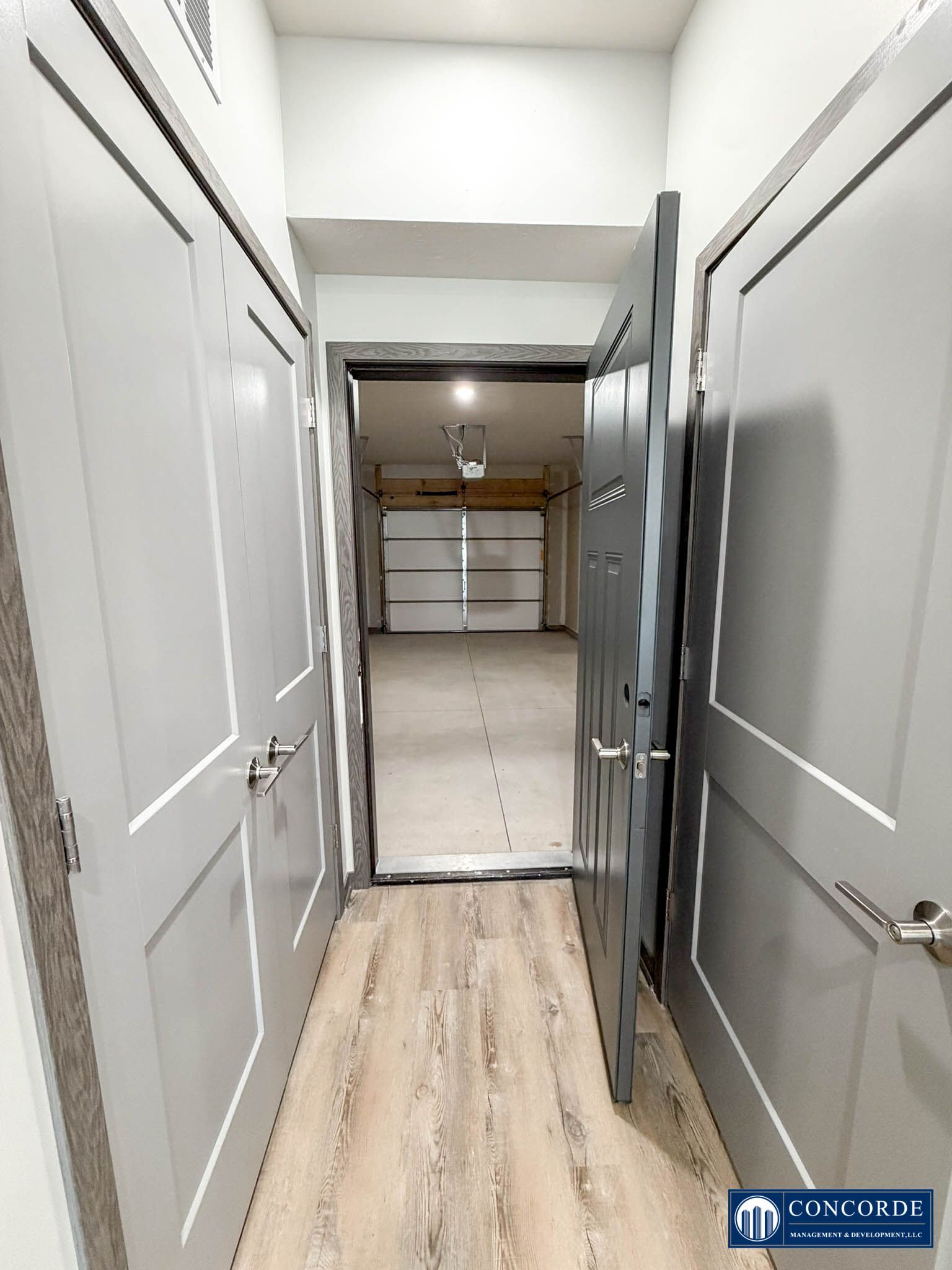 Narrow hallway with white doors leading to a garage or storage area, viewed from indoors.
