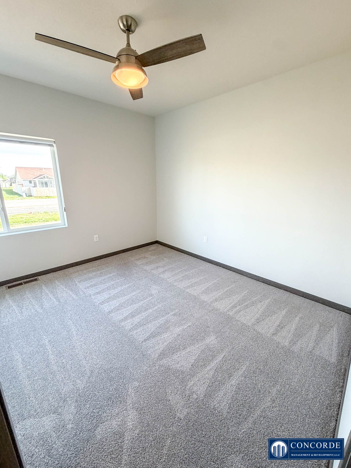 Empty white bedroom with carpet, window, and ceiling fan light