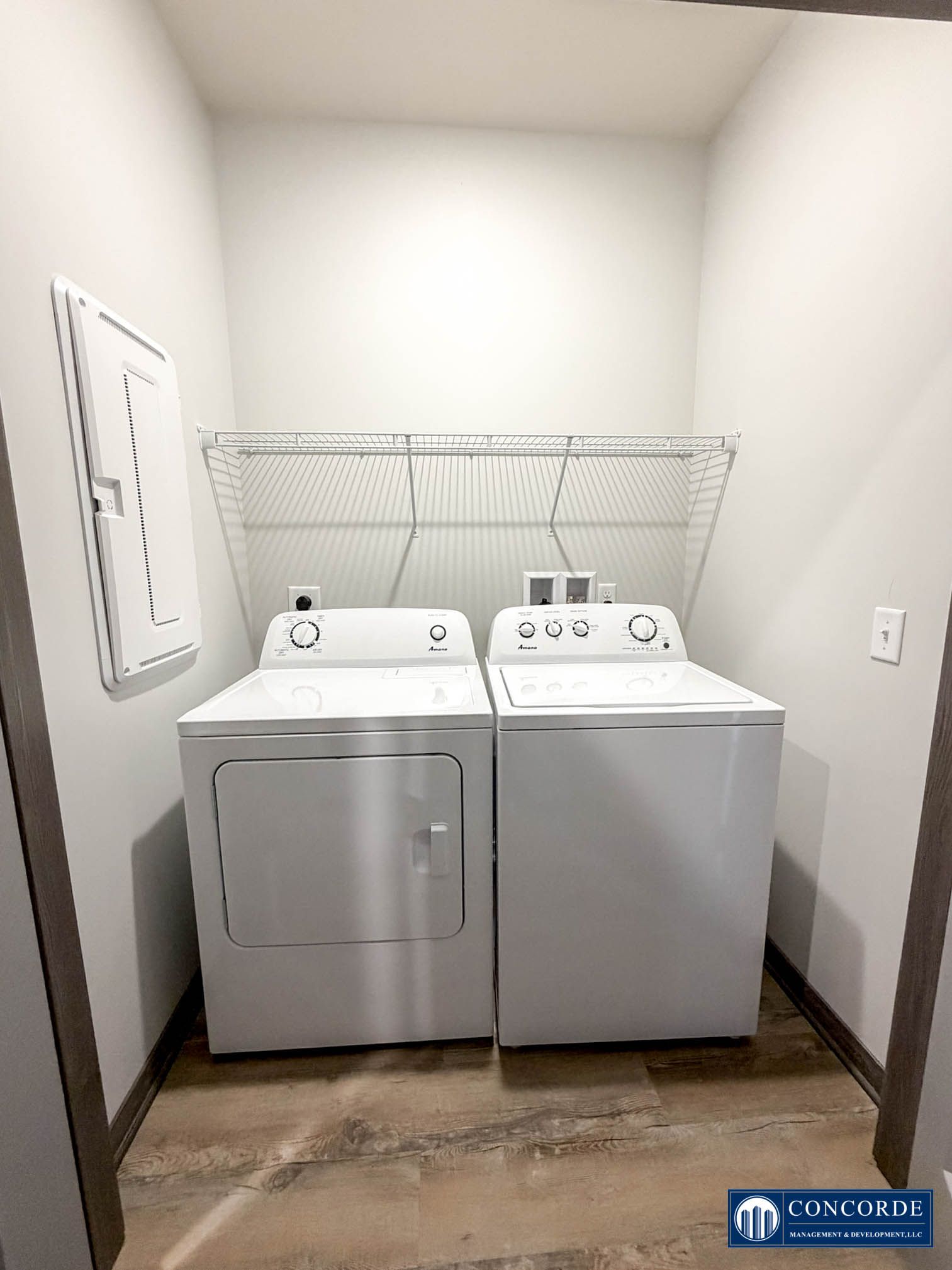 Laundry room with a washer and dryer under a wire shelf in a small white closet.