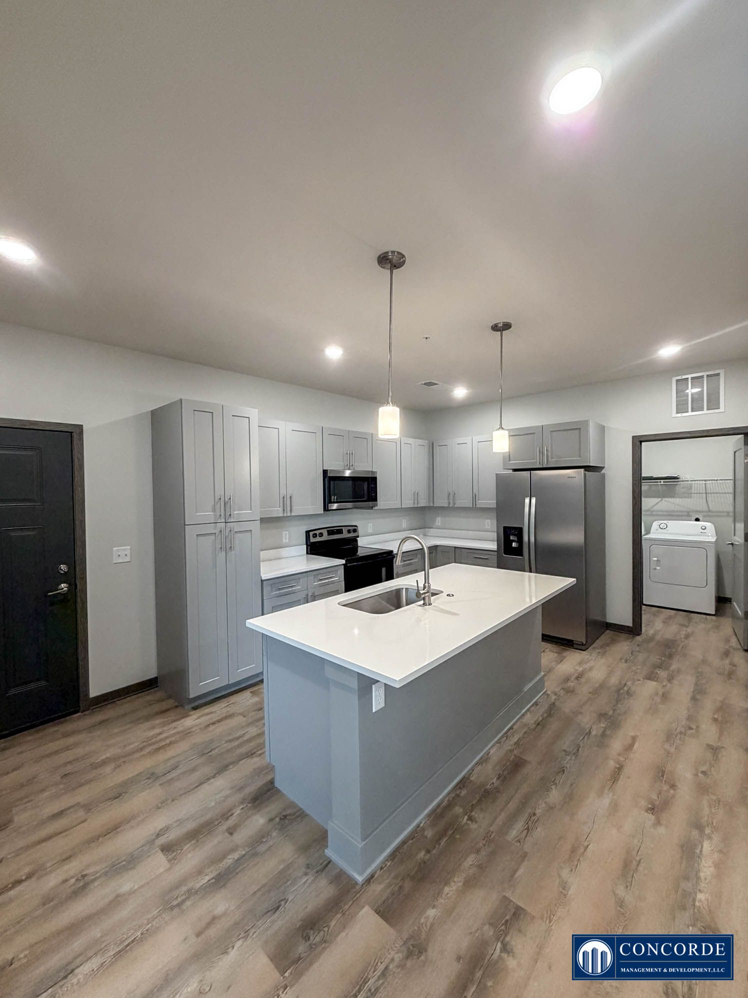 Modern kitchen with white cabinets, gray island, stainless appliances, and wood-look flooring