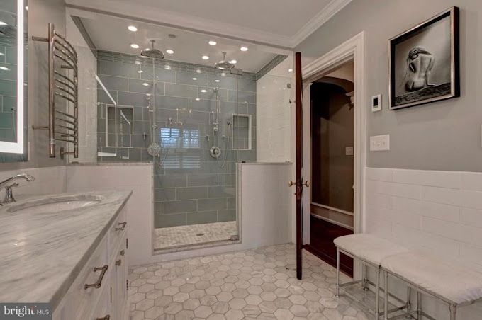 A bathroom with a walk in shower , sink , and bench.