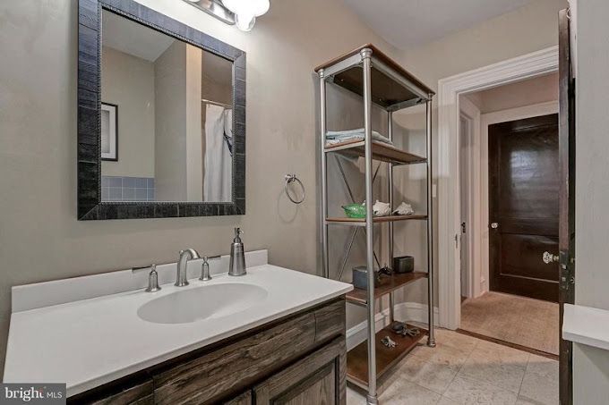 A bathroom with a sink , mirror and shelf.