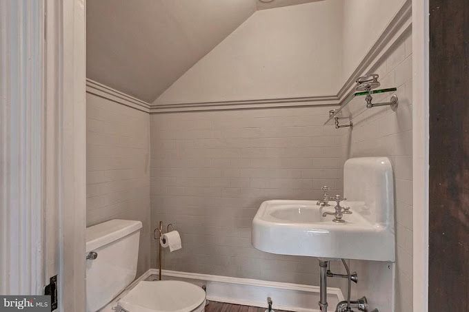 A bathroom with a toilet , sink and mirror.