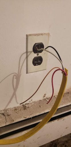 A close up of a power outlet with wires coming out of it.