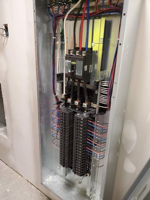 A electrical panel with a lot of wires coming out of it.
