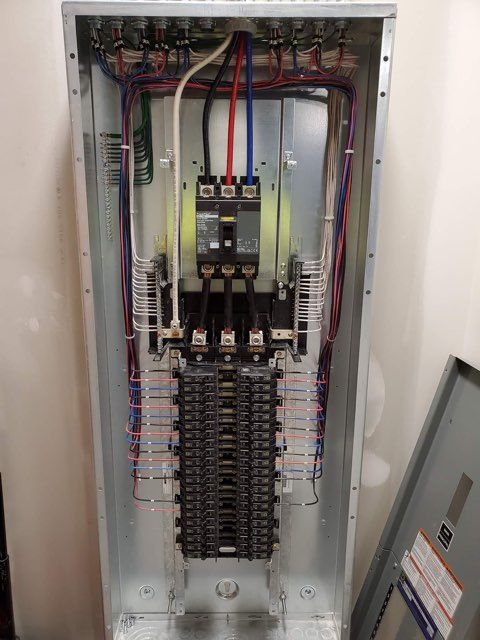 A electrical panel with a lot of wires coming out of it.