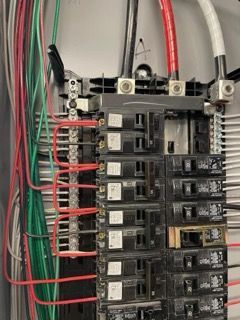 A close up of a electrical panel with a lot of wires coming out of it.