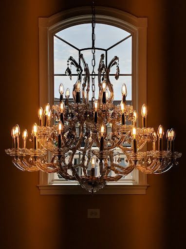 A large chandelier is hanging from the ceiling in front of a window.