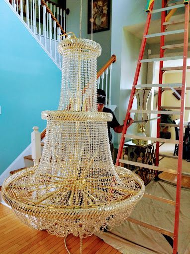 A man is standing next to a large chandelier in a living room.