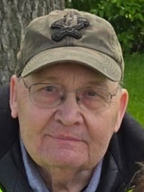 Man wearing glasses and a cap, looking directly at the camera.
