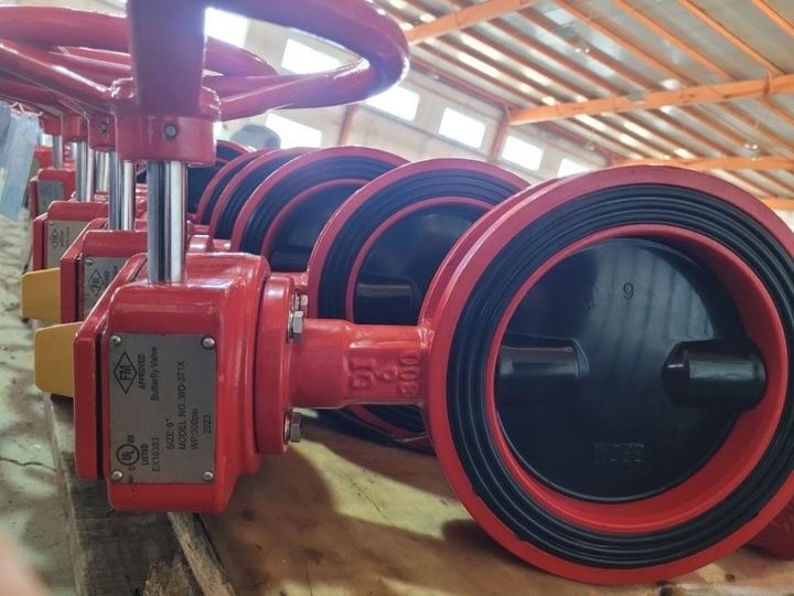 A row of red valves are lined up in a warehouse
