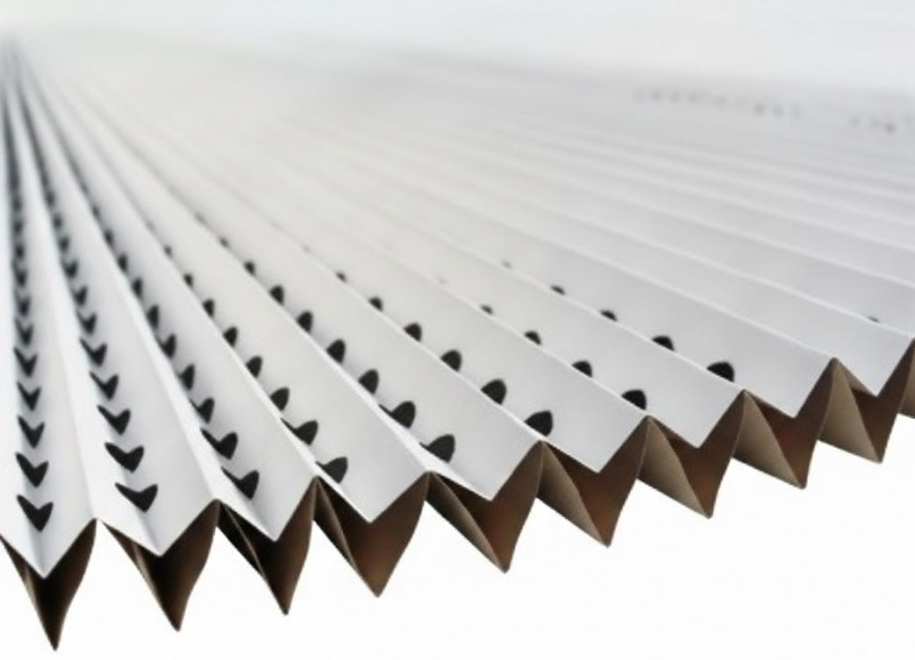 Filtro dell'aria bianco plissettato con fori scuri nelle pieghe, su sfondo bianco.