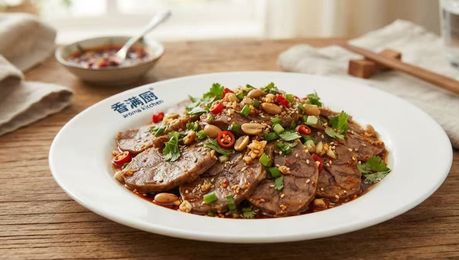 Plated sliced beef in spicy sauce topped with chopped chilies and herbs on a white dish