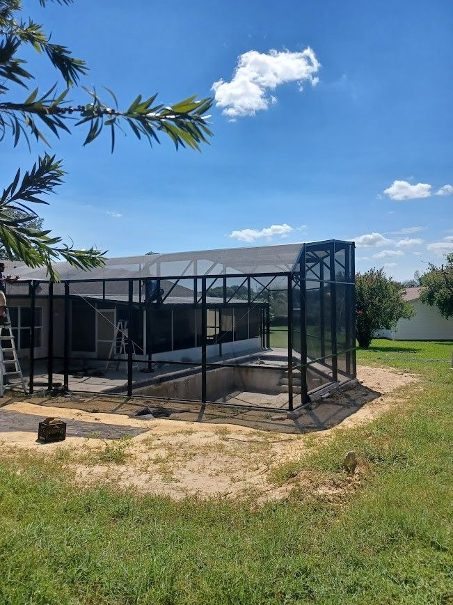 A screened in pool is being built in the backyard of a house.
