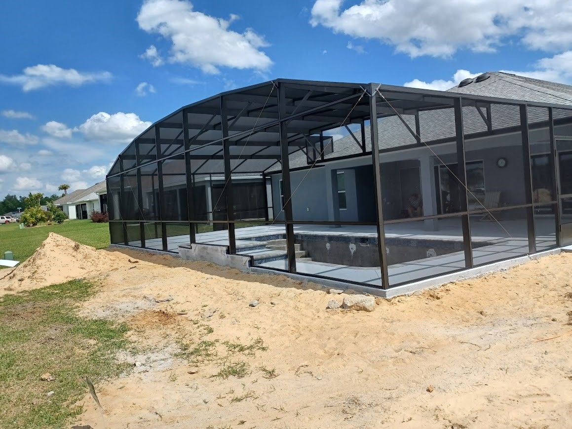 A swimming pool enclosure is being built in the backyard of a house.
